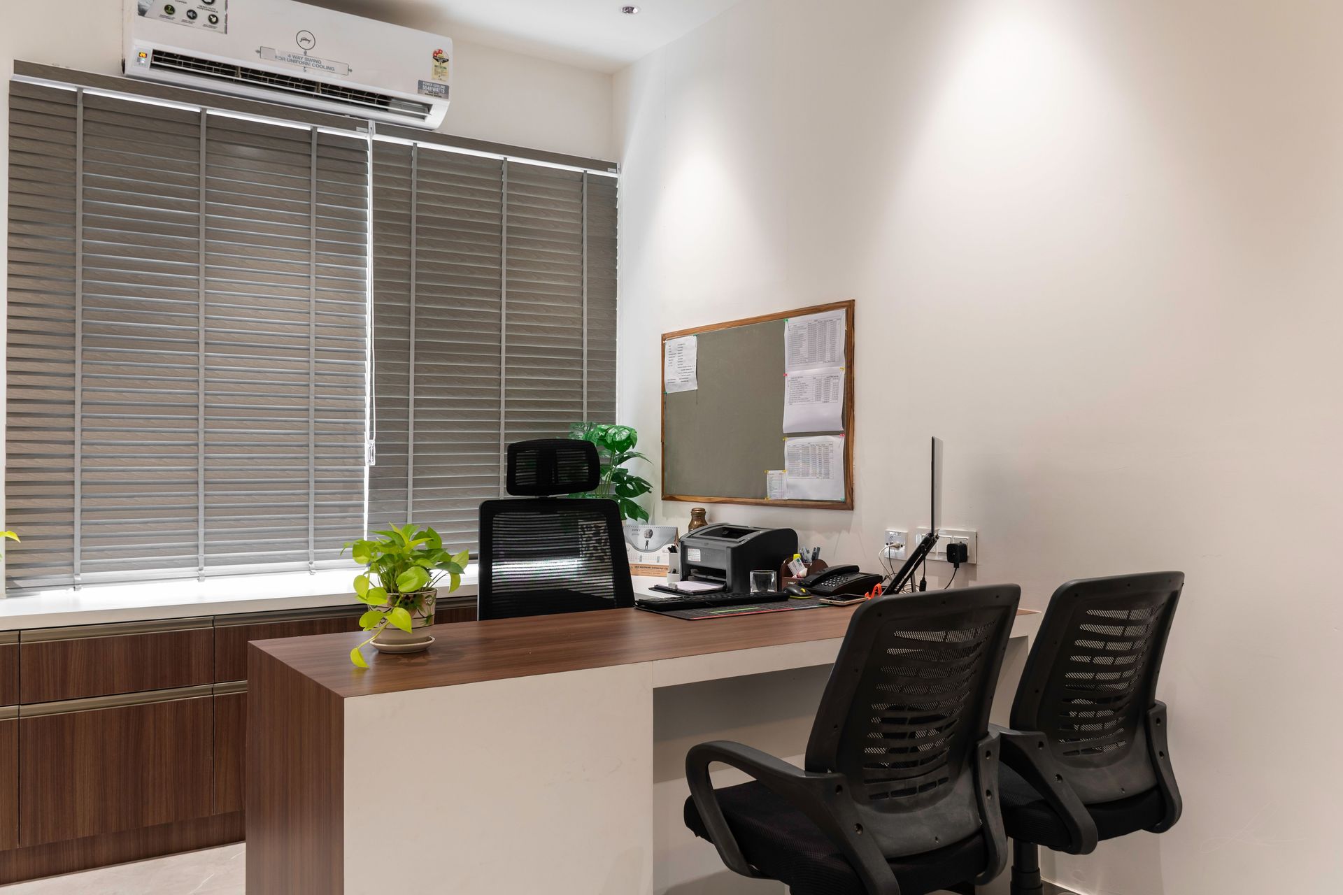 Bright and modern office interior with desk, chairs, and potted plants for a fresh work environment.